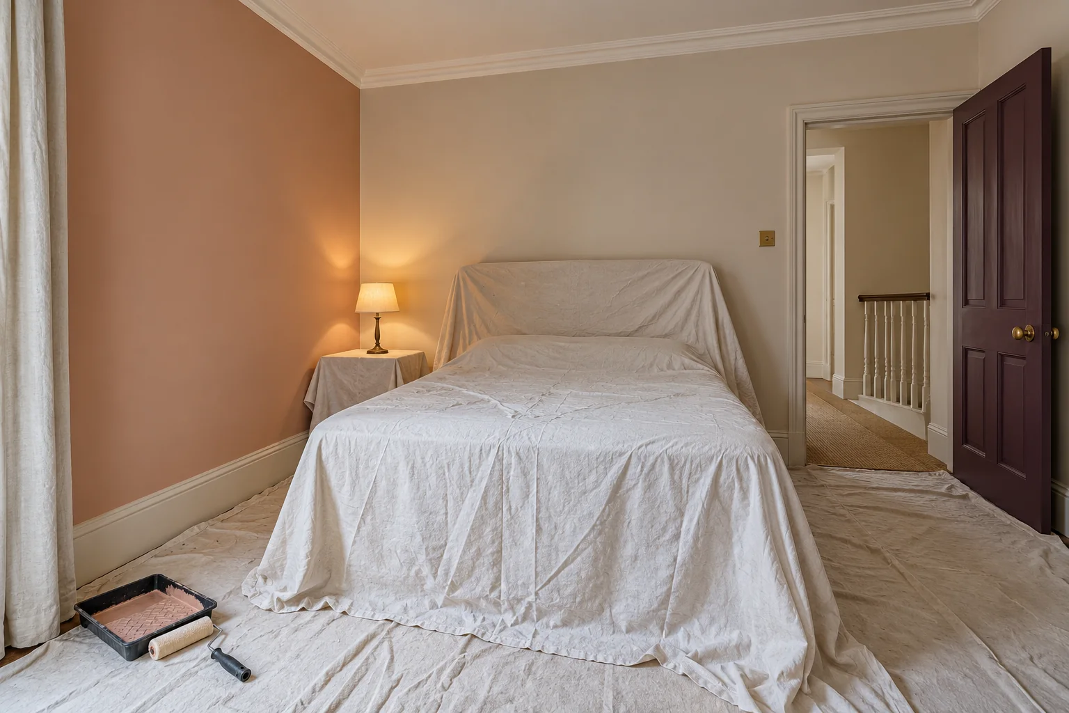 Small period guest room with furniture protected for repainting and soft coloured walls